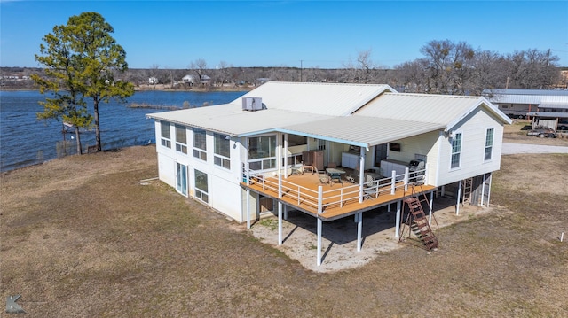 back of property with a deck with water view and metal roof