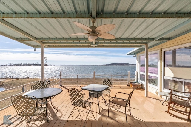wooden terrace with outdoor dining area, a water view, and a ceiling fan