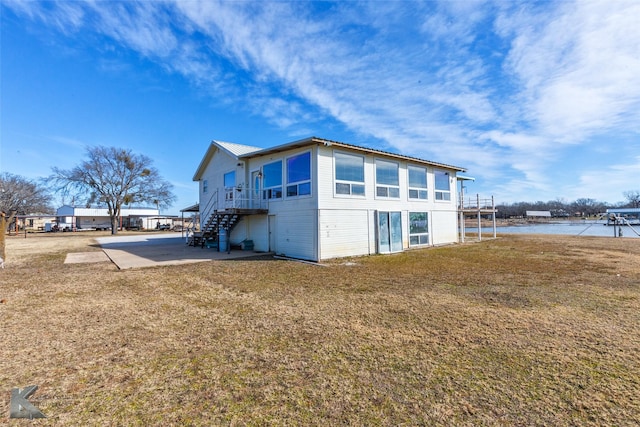 view of side of home featuring a patio area, a yard, and a water view