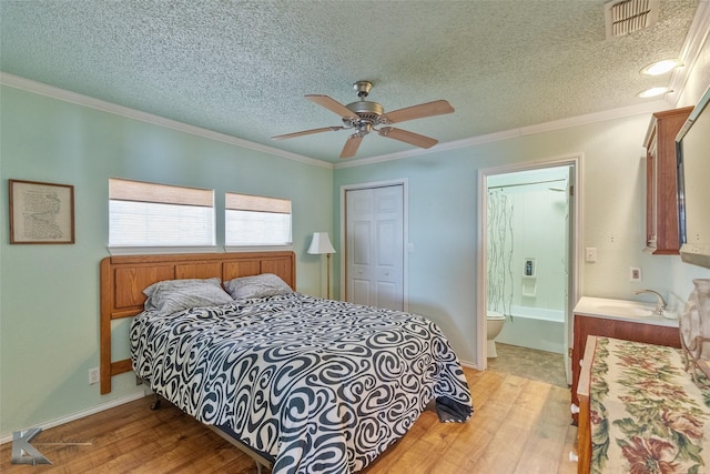 bedroom with crown molding, ceiling fan, sink, light wood-type flooring, and a textured ceiling