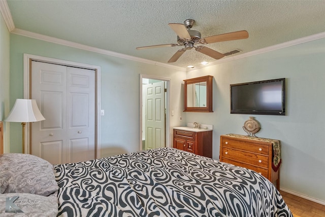 bedroom featuring a textured ceiling, a closet, ceiling fan, and ornamental molding