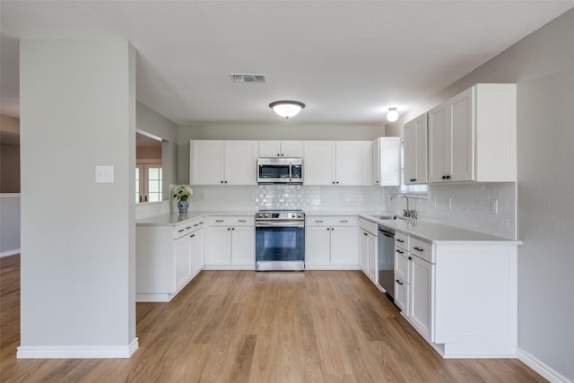 kitchen featuring light hardwood / wood-style flooring, appliances with stainless steel finishes, sink, white cabinets, and tasteful backsplash