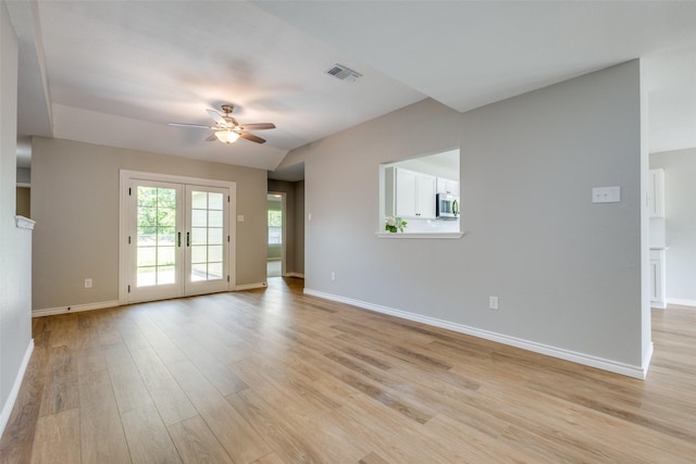 empty room with light hardwood / wood-style floors, vaulted ceiling, ceiling fan, and french doors