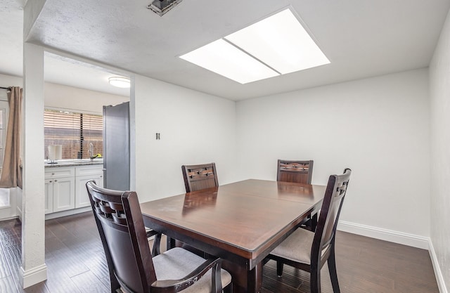 7221 Chinaberry Rd, Dallas, TX 75249 - dining area featuring baseboards, dark wood-type flooring, and a skylight