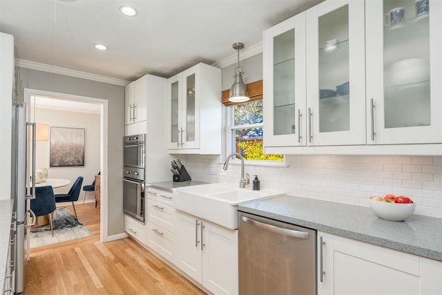 kitchen featuring light wood-type flooring, white cabinetry, pendant lighting, and appliances with stainless steel finishes