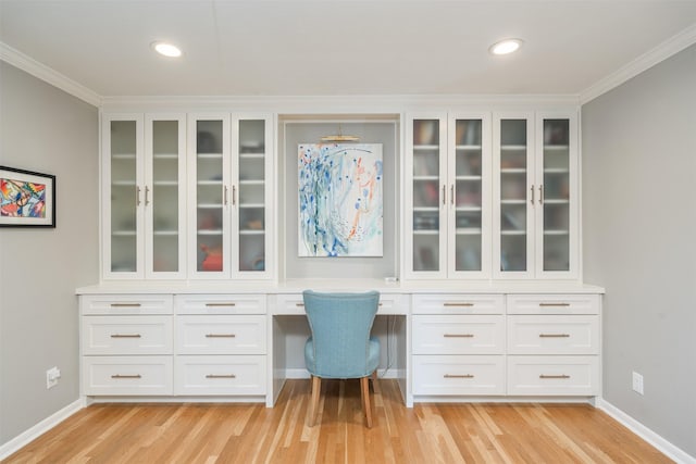 office with light wood-type flooring, built in desk, and crown molding