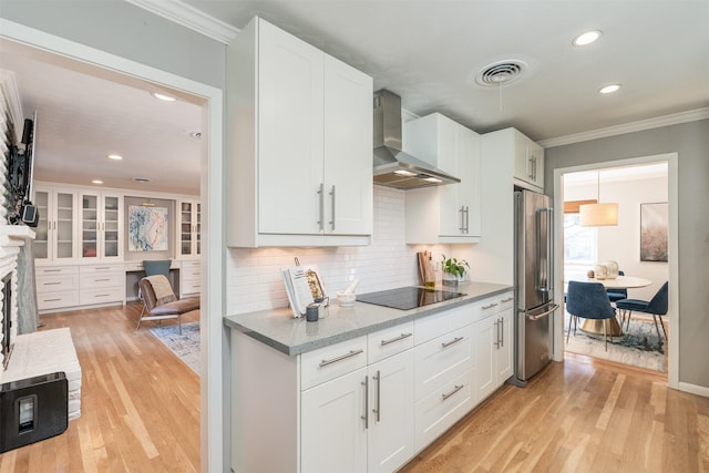 kitchen featuring white cabinetry, high end fridge, wall chimney range hood, black electric cooktop, and light hardwood / wood-style floors