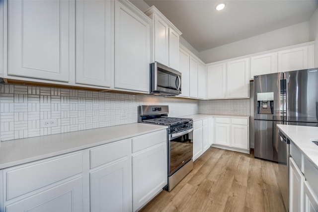 kitchen featuring white cabinetry, appliances with stainless steel finishes, light hardwood / wood-style floors, and backsplash