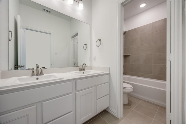 full bathroom with tiled shower / bath combo, vanity, tile patterned floors, and toilet