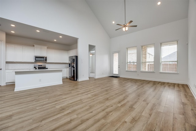 unfurnished living room featuring high vaulted ceiling, ceiling fan, and light hardwood / wood-style flooring