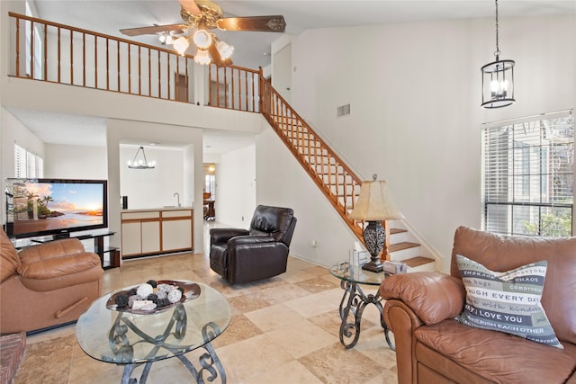 living room with ceiling fan with notable chandelier, sink, a wealth of natural light, and a towering ceiling