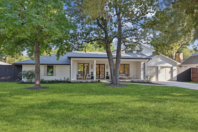 view of front of property featuring a garage, covered porch, and a front yard