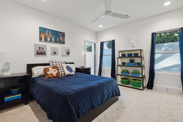 bedroom featuring ceiling fan, light carpet, and multiple windows