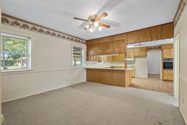 kitchen with light colored carpet, oven, a textured ceiling, and kitchen peninsula