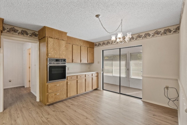 kitchen featuring a chandelier, black oven, a textured ceiling, and light hardwood / wood-style flooring