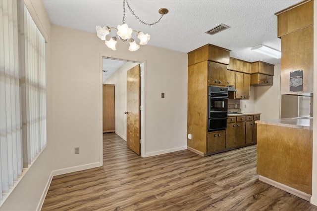 kitchen featuring pendant lighting, dark hardwood / wood-style flooring, a chandelier, stainless steel gas cooktop, and a textured ceiling