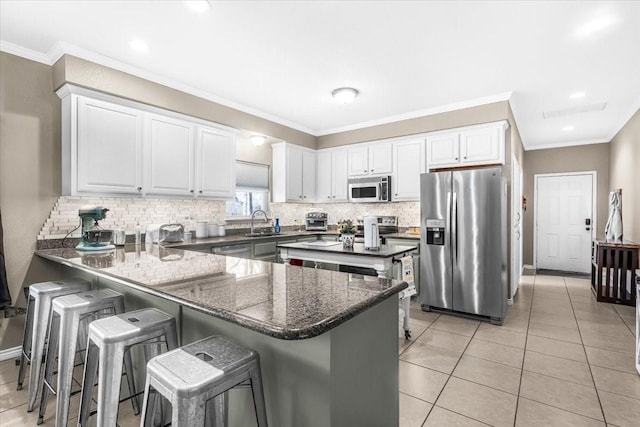 kitchen with stainless steel appliances, white cabinetry, kitchen peninsula, and a kitchen breakfast bar