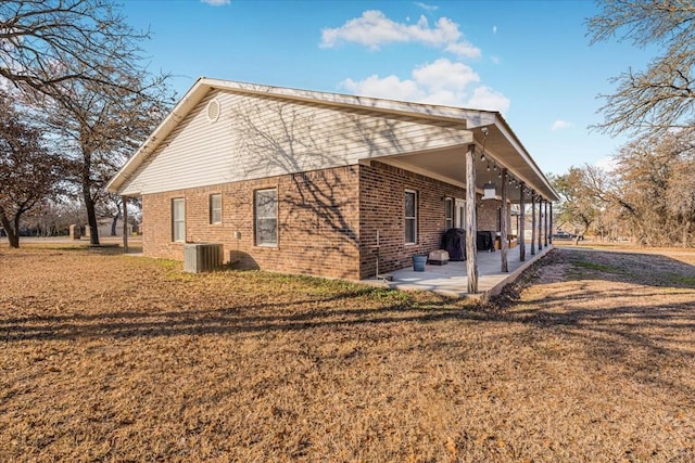 view of side of home featuring cooling unit, a patio, and a lawn