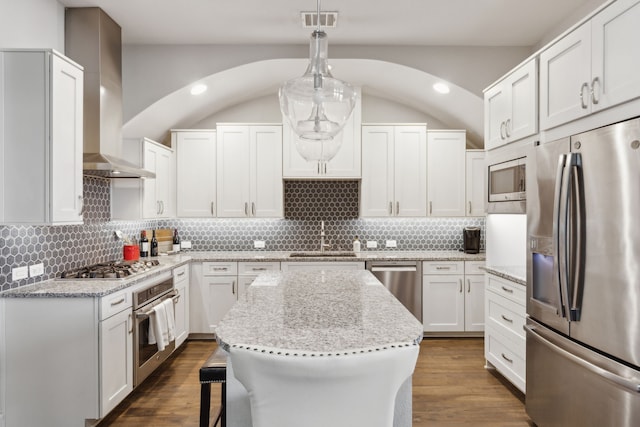 kitchen featuring a center island, range hood, white cabinets, sink, and stainless steel appliances