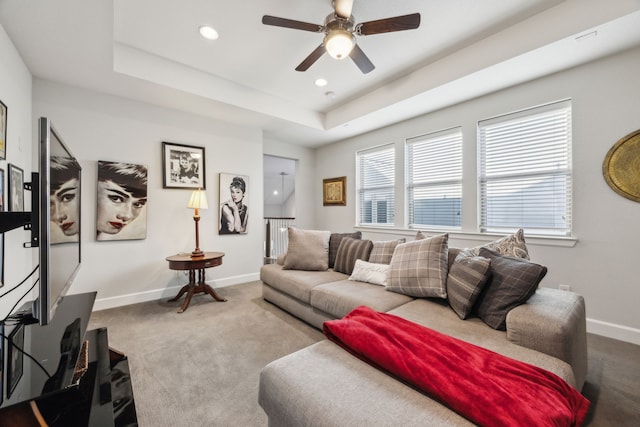 carpeted living room featuring ceiling fan and a raised ceiling