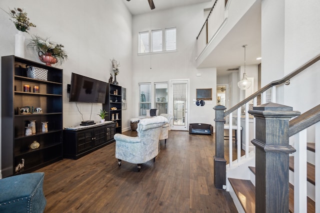 living room featuring ceiling fan, a high ceiling, and dark hardwood / wood-style floors