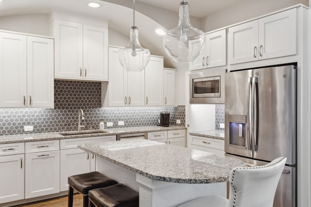 kitchen featuring sink, hanging light fixtures, a kitchen bar, and appliances with stainless steel finishes