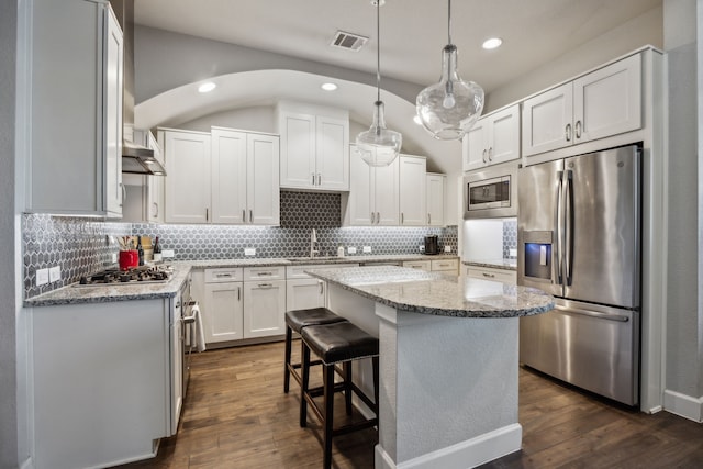 kitchen with a center island, appliances with stainless steel finishes, light stone countertops, hanging light fixtures, and white cabinets