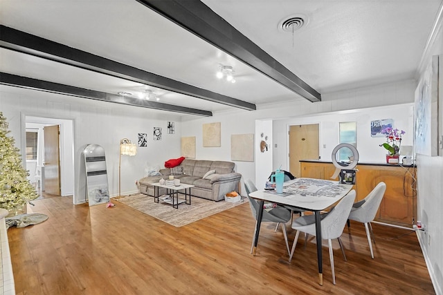 dining space with wood-type flooring and beam ceiling