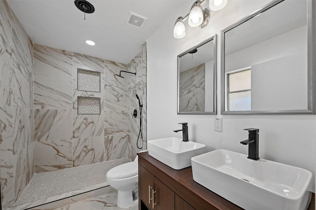 bathroom featuring vanity, toilet, and tiled shower