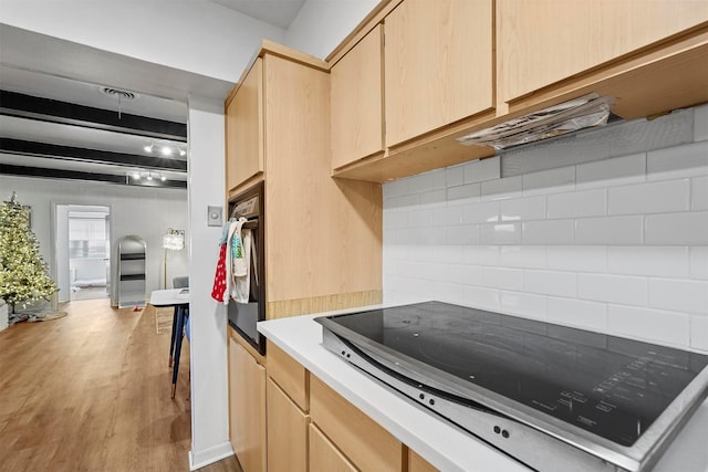 kitchen with light brown cabinetry, light hardwood / wood-style floors, backsplash, and black appliances