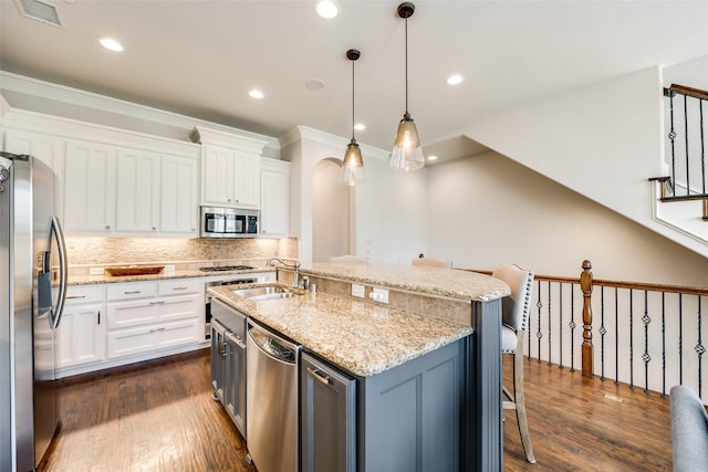 kitchen with sink, appliances with stainless steel finishes, a kitchen breakfast bar, an island with sink, and white cabinets