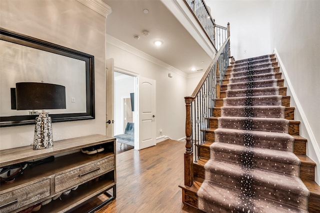 staircase with ornamental molding and wood-type flooring