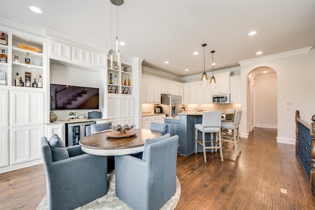 dining room with crown molding, dark hardwood / wood-style floors, and bar area