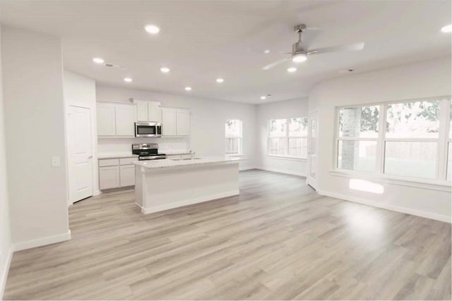 kitchen featuring appliances with stainless steel finishes, white cabinetry, sink, a center island with sink, and light wood-type flooring