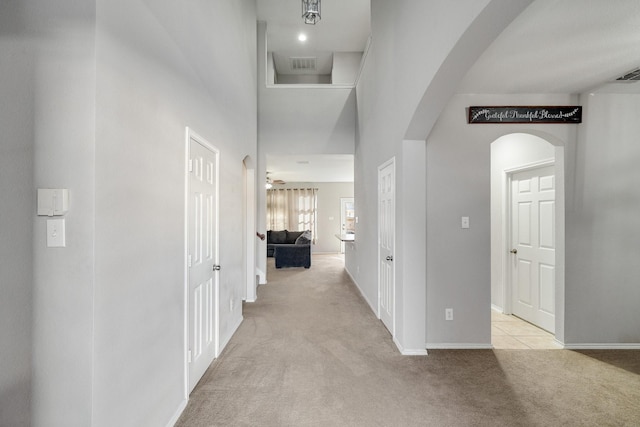 hallway featuring a high ceiling and light carpet