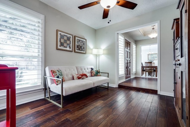 living room featuring ceiling fan with notable chandelier, dark hardwood / wood-style floors, and a textured ceiling