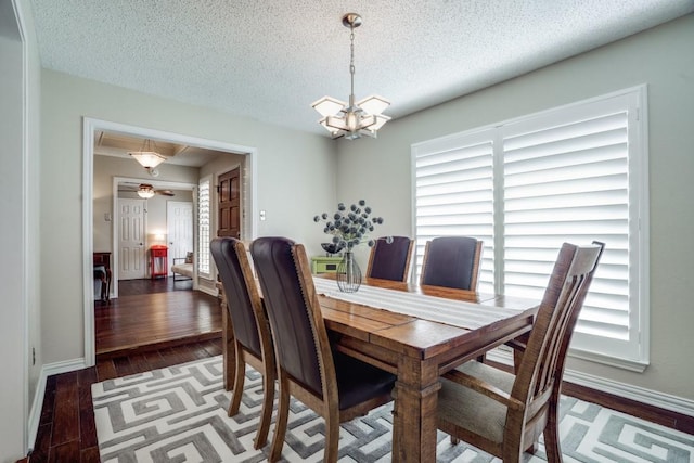 dining area with a notable chandelier, dark hardwood / wood-style floors, and a textured ceiling