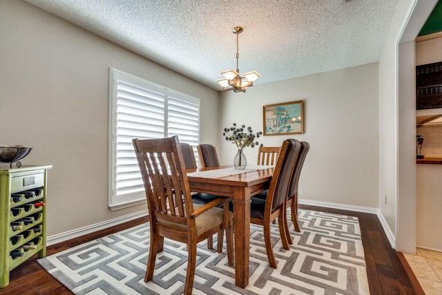 dining space with hardwood / wood-style flooring, a textured ceiling, and a chandelier