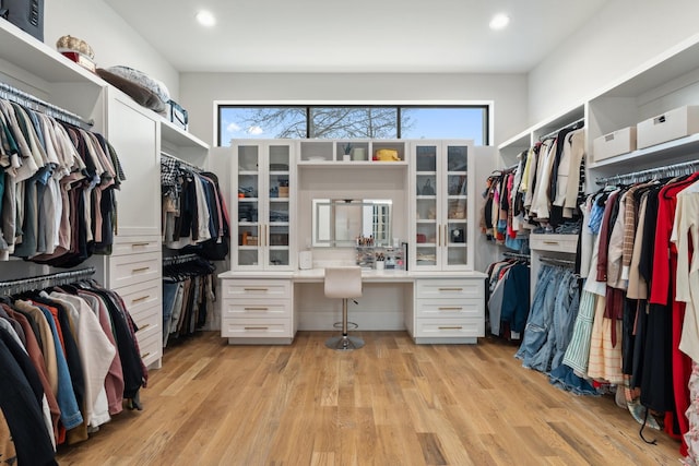 walk in closet featuring built in desk and light hardwood / wood-style floors