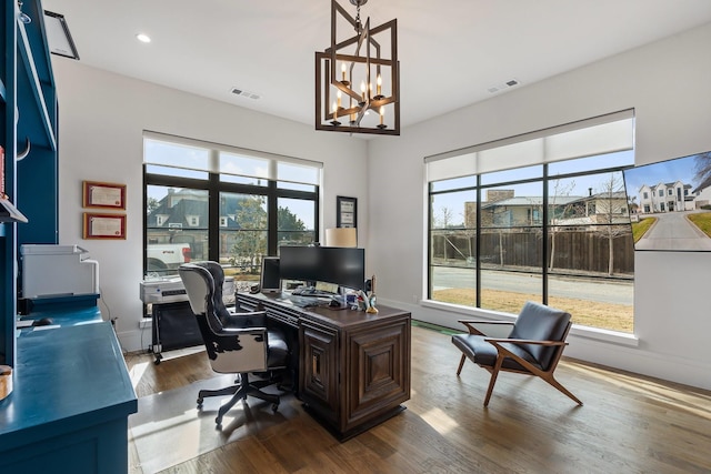 office with hardwood / wood-style flooring and an inviting chandelier