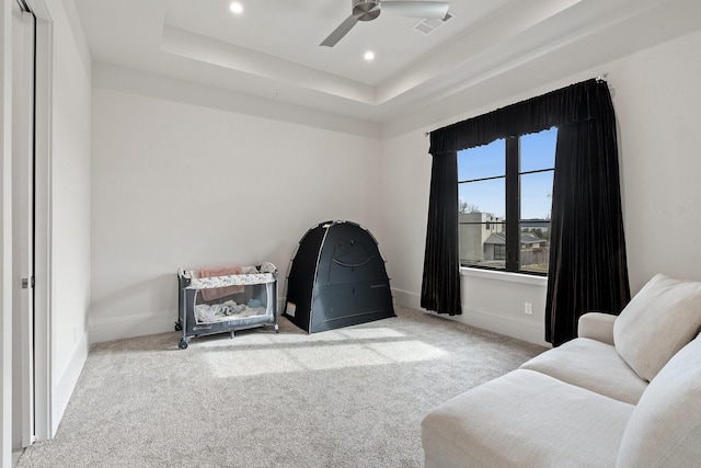 sitting room featuring light carpet, ceiling fan, and a tray ceiling