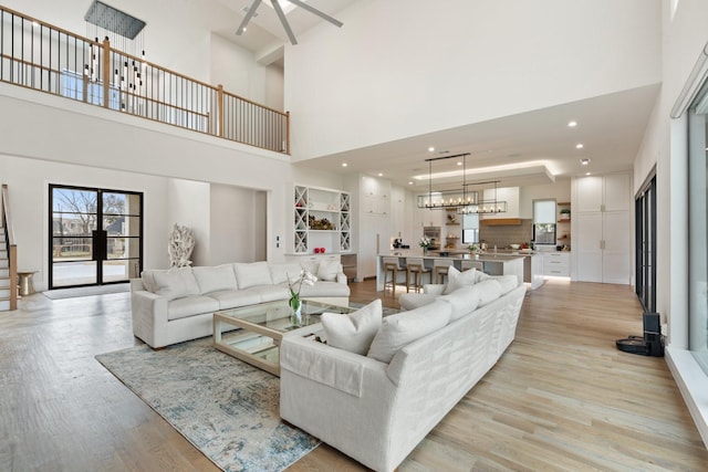 living room with a towering ceiling, light hardwood / wood-style flooring, and an inviting chandelier