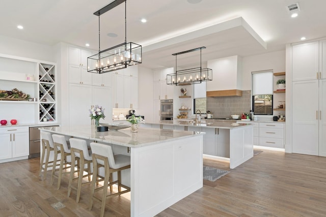 kitchen with pendant lighting, a spacious island, white cabinets, a breakfast bar, and decorative backsplash