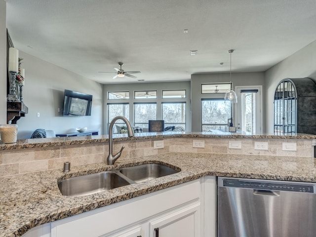 kitchen with light stone counters, stainless steel dishwasher, sink, and white cabinets