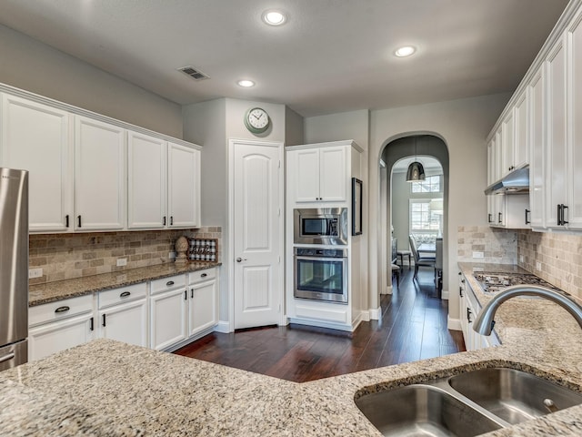 kitchen with white cabinetry, appliances with stainless steel finishes, light stone countertops, and sink