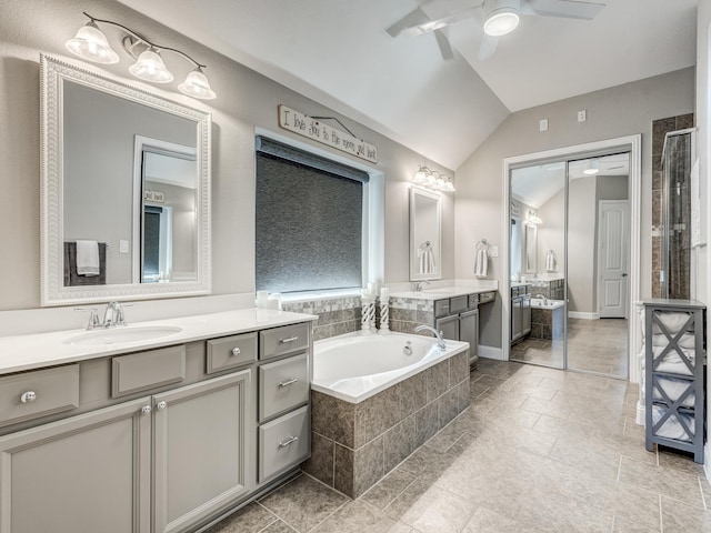 bathroom featuring lofted ceiling, vanity, ceiling fan, and tiled tub