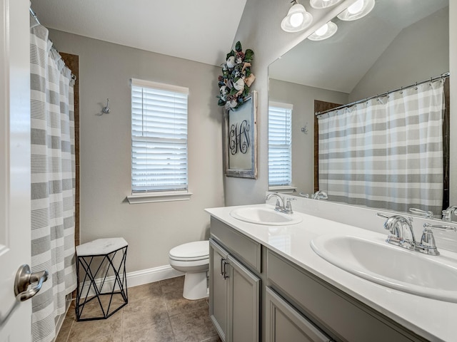 bathroom featuring vanity, vaulted ceiling, tile patterned floors, and toilet