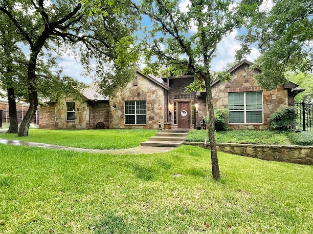 view of front of home with stone siding, fence, and a front yard