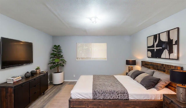 bedroom with a textured ceiling and light wood-type flooring