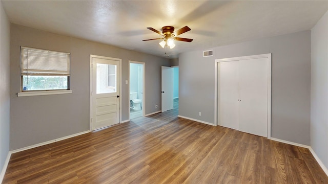 unfurnished bedroom featuring a closet, ceiling fan, ensuite bathroom, and wood-type flooring